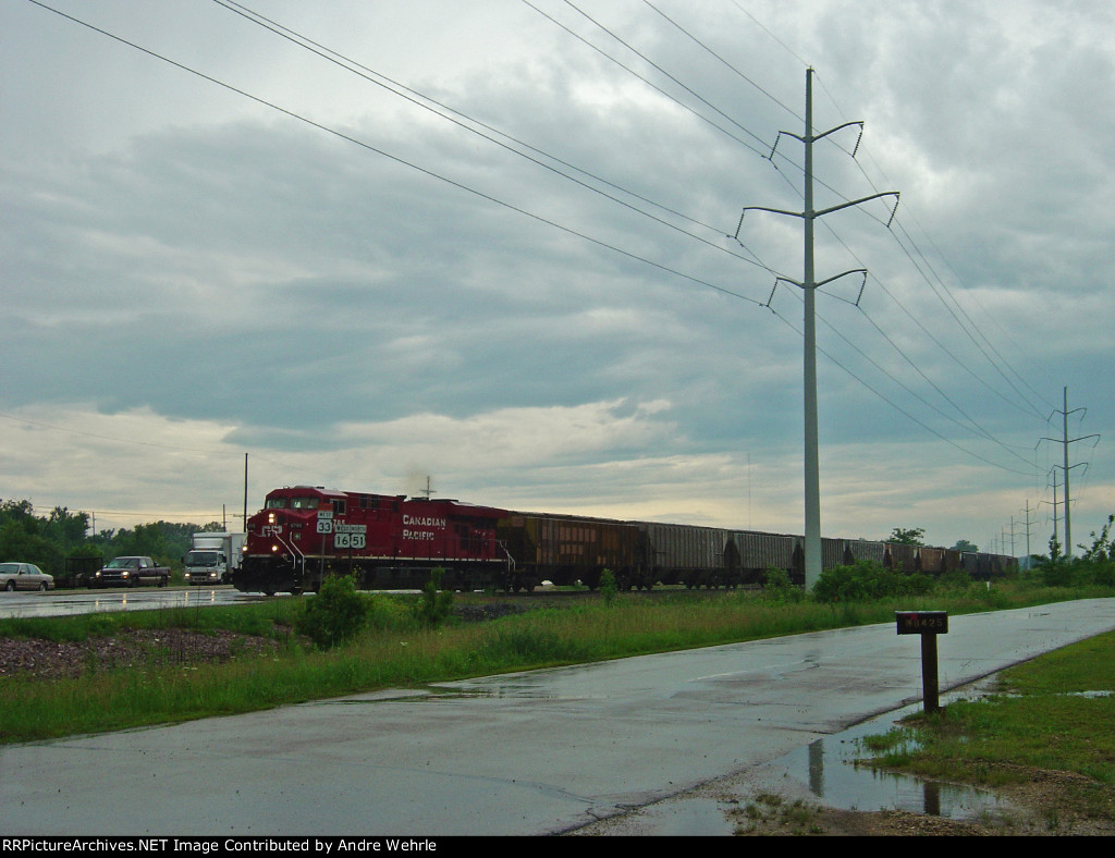 CP 8795 leads a detoured unit grain train across Highway 51 on the Madison branch